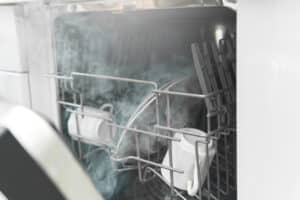 Closeup of dishwasher with a plates, cups and other dishware
