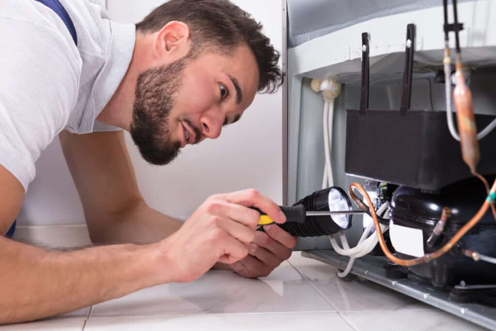 Photo Of Male Technician Repairing Refrigerator With Screwdriver